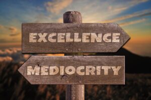 Wooden sign post pointing towards 'Excellence' on the right, and 'Mediocrity' on the left. It is suggesting that competitive aikido is good because it drives us towards excellence and away from mediocrity